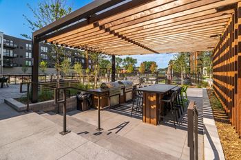 an outdoor patio with a barbecue grill and tables and chairs